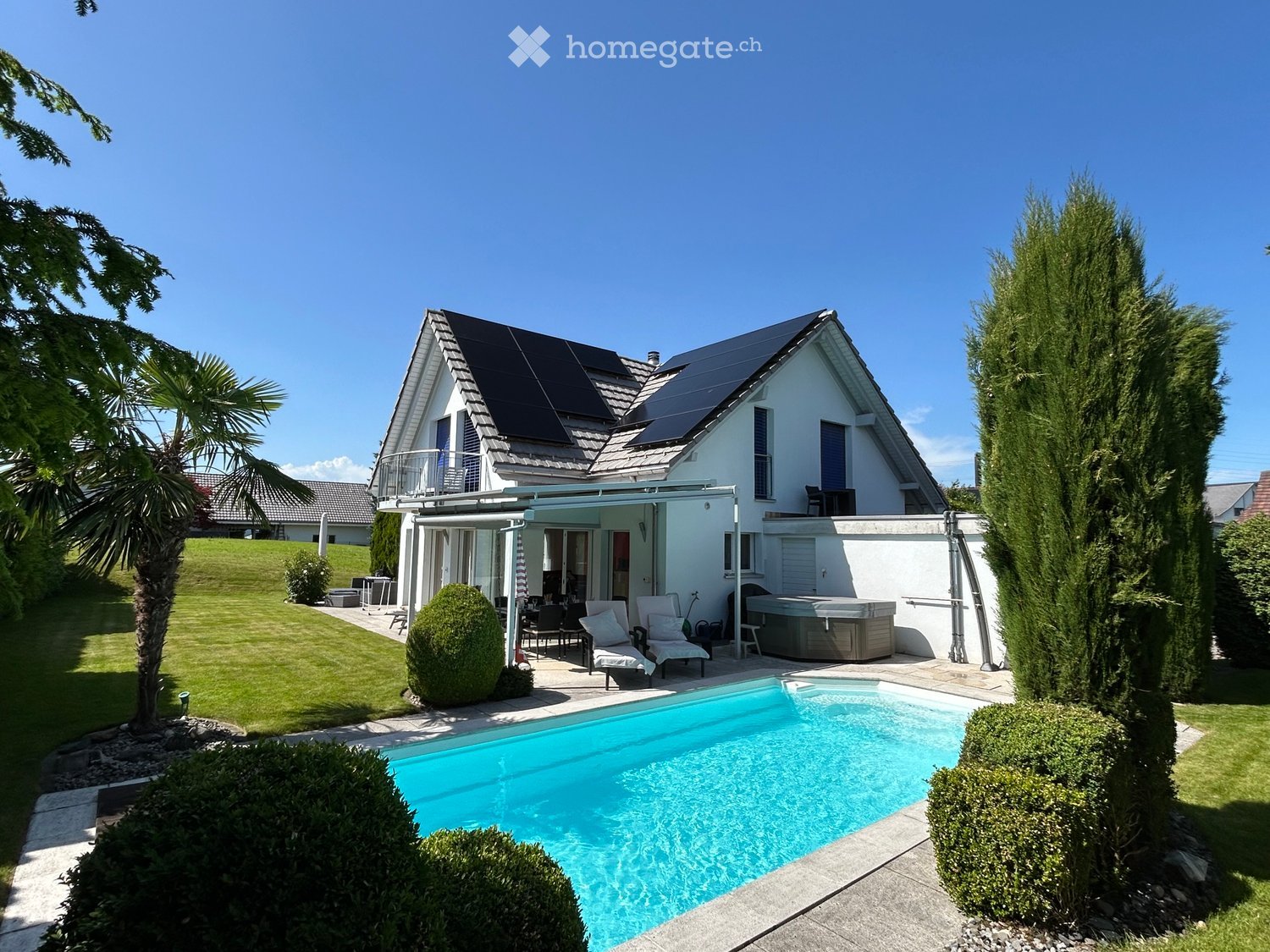 Modern house with solar panels, swimming pool, and a covered terrace with outdoor seating.