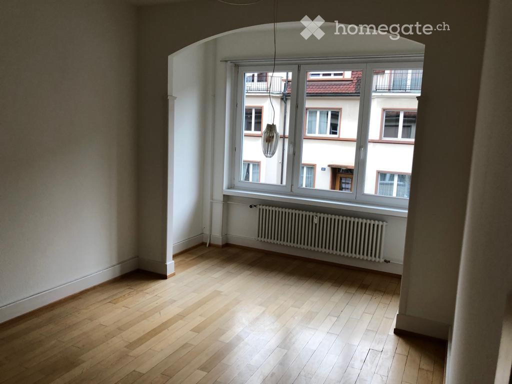 empty room, wooden floor, white walls, arch window with view of a building, radiator
