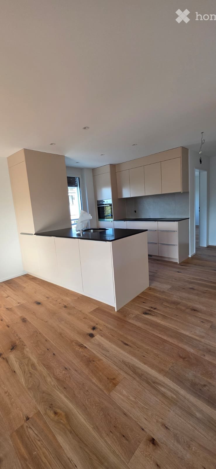 Modern kitchen with white cabinets, black countertops, and wooden floors.