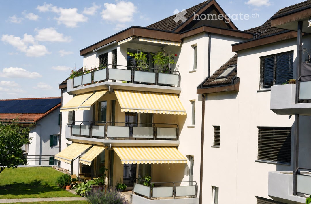Modern multi-story residential building with balconies, striped awnings, and greenery.