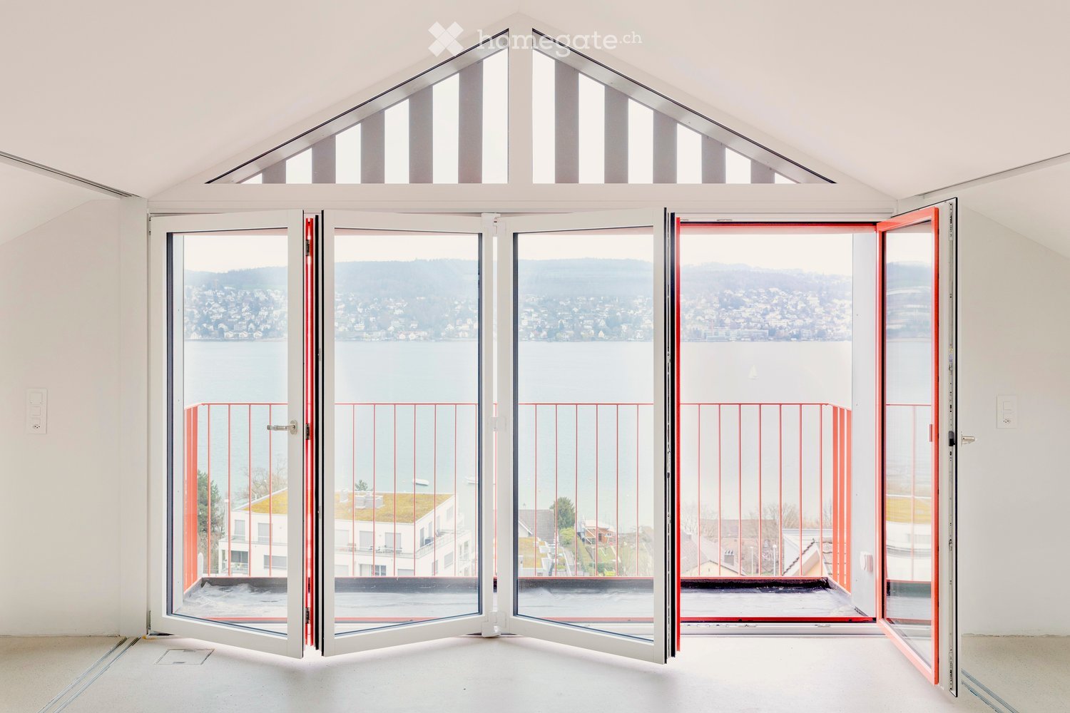 open folding doors, balcony, glass balcony railing, city view, water body in the distance