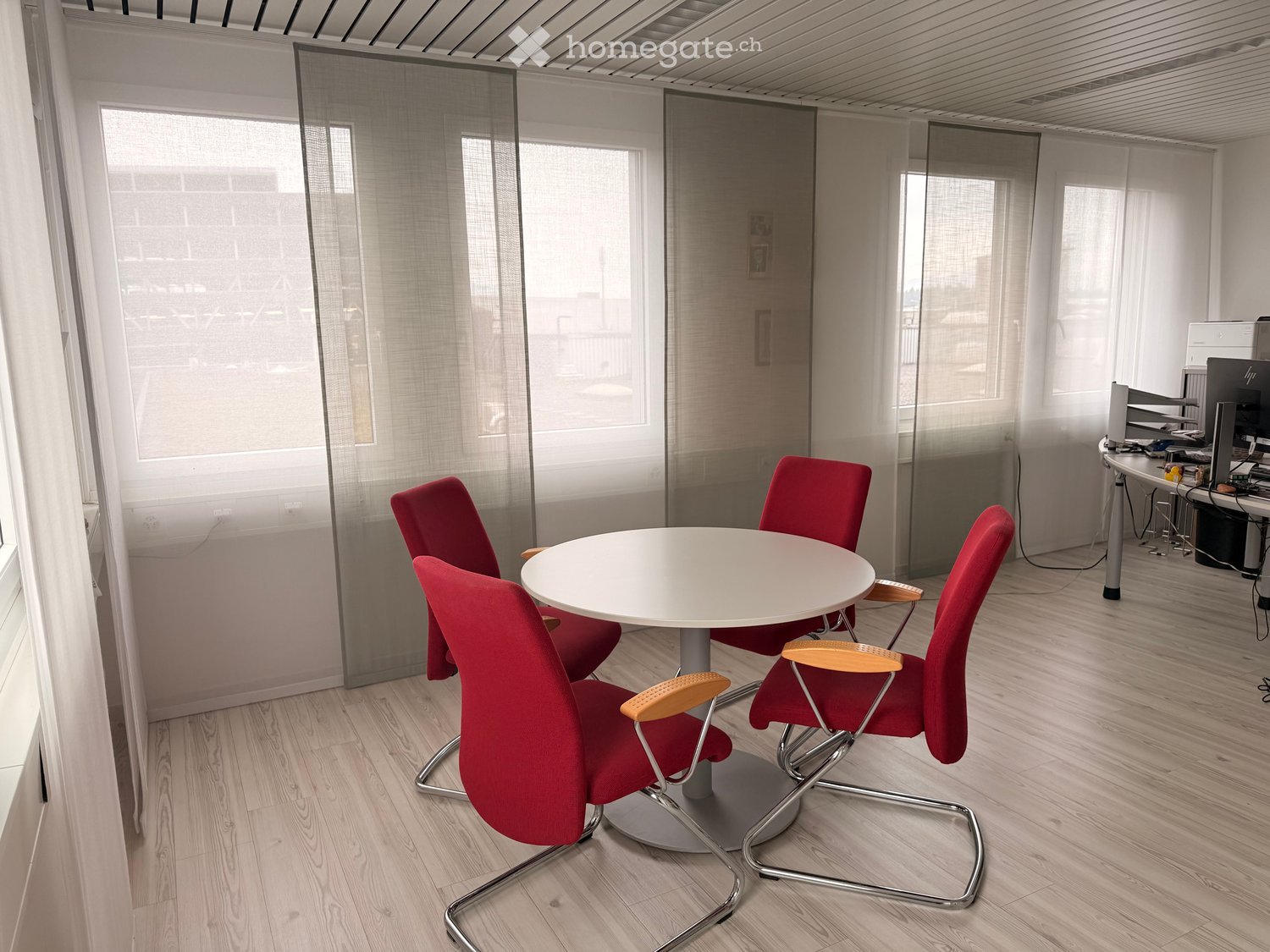 white round table with 4 red chairs, wooden floor, large windows, white curtains, white walls