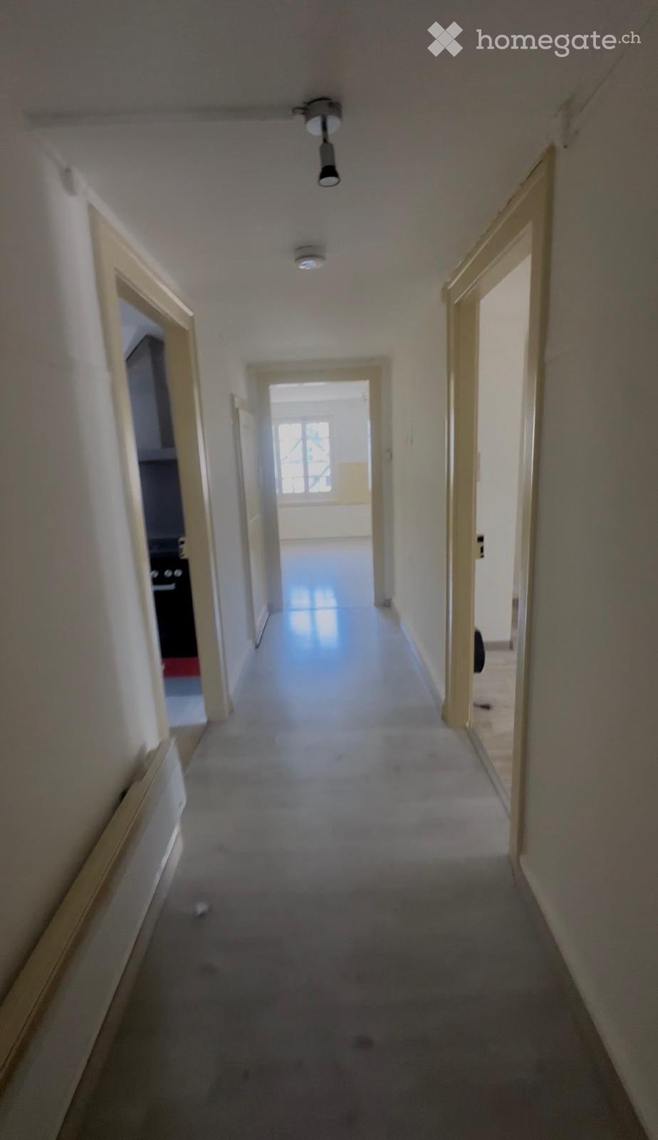 Empty hallway with carpeted floor, white walls, and several open doors leading to other rooms.