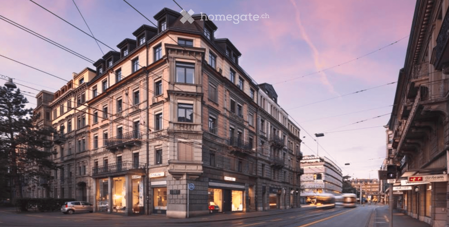 Multi-story urban building with classic architecture, large windows, and ground-floor storefronts. The building features ornate detailing and is situated on a street with visible traffic and surrounding structures.
