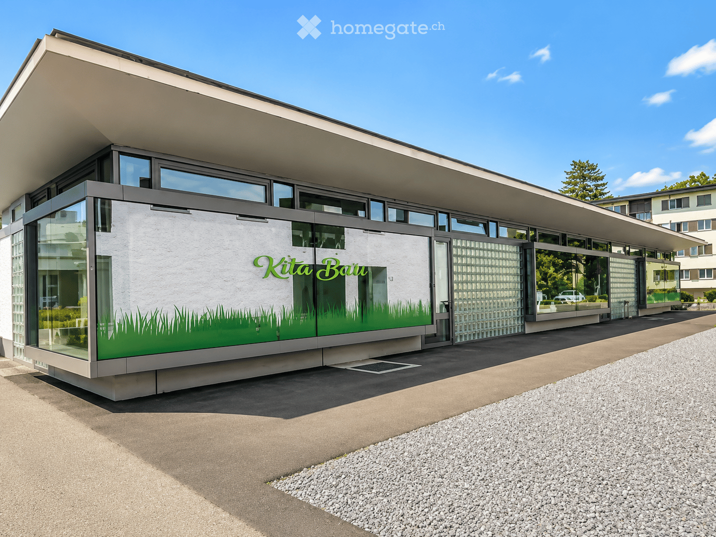 Modern building with large glass windows and a flat roof, featuring a green graphic design on the facade.