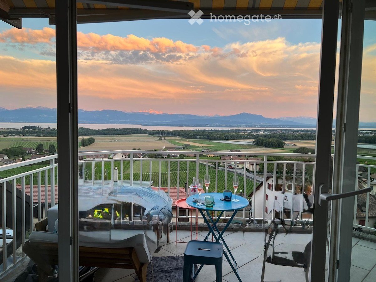 Balcony with scenic view of mountains and countryside, furnished with a small table, chairs, and a stool.