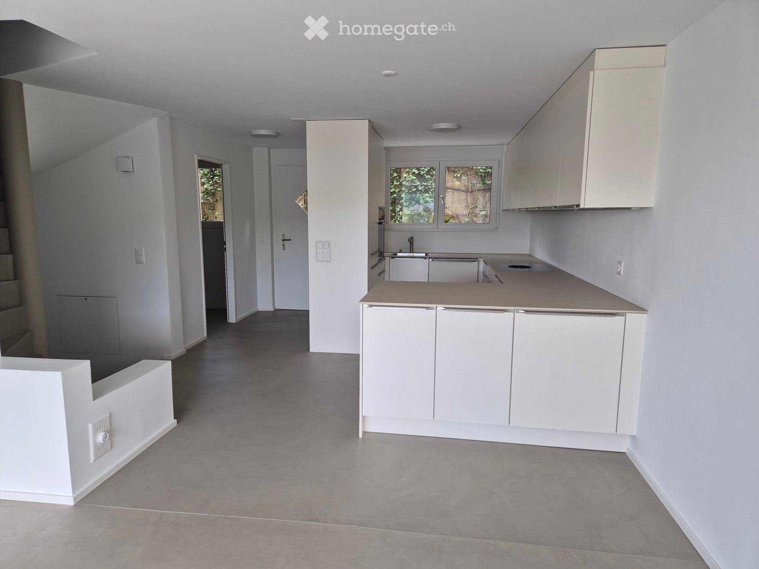 Empty kitchen with white cabinets, a central island, and grey tiled flooring. No appliances or furniture are present.