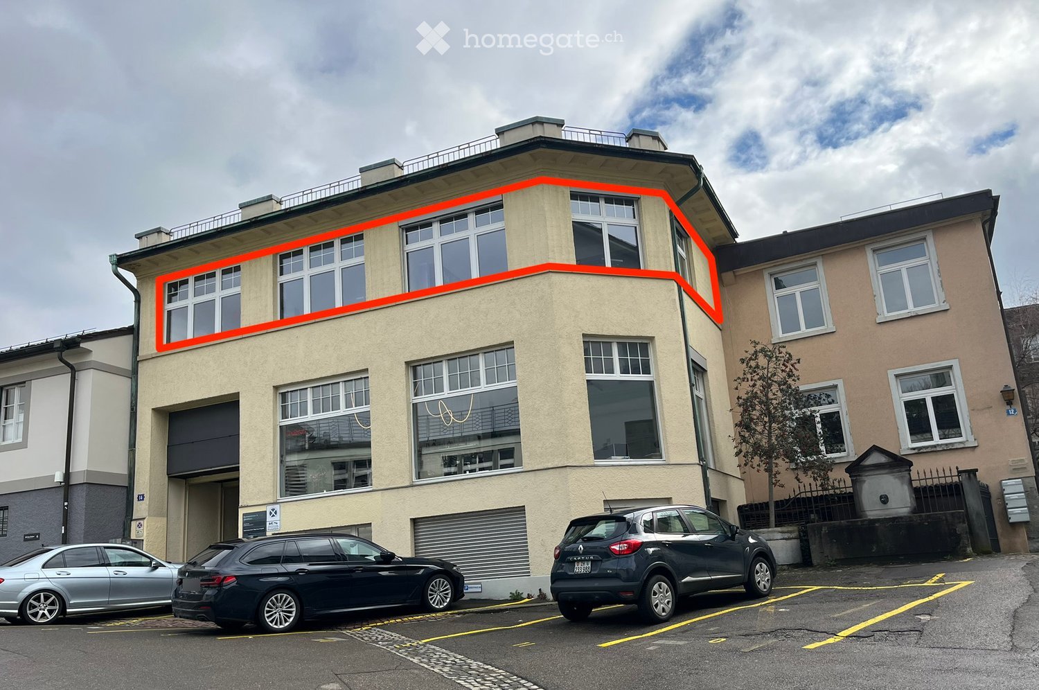 3 story building, beige exterior, glass windows, highlighted portion with orange line, garage on the ground floor, 3 cars parked in front