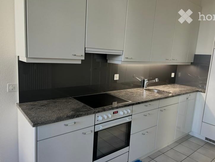 Modern kitchen with white cabinets, granite countertop, built-in stove, and sink.