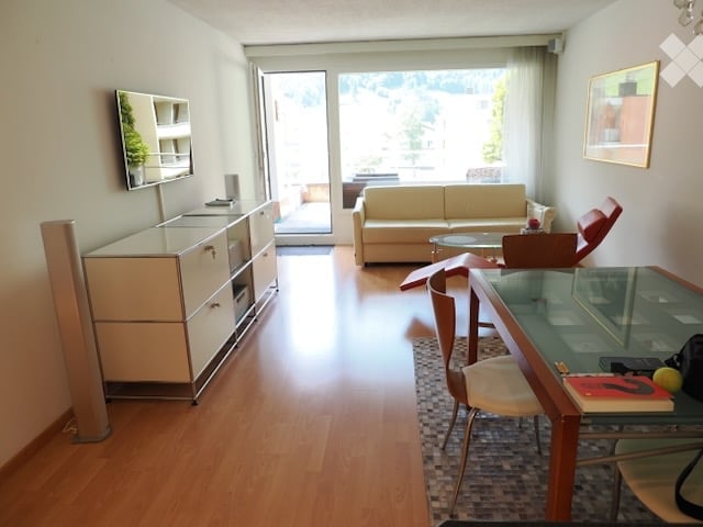 Bright, modern living room with light-colored furniture, large windows, and a view of the outdoors.