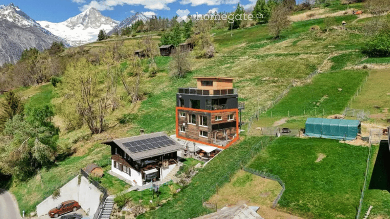 House with solar panels, wooden exterior, surrounded by green grass and mountains