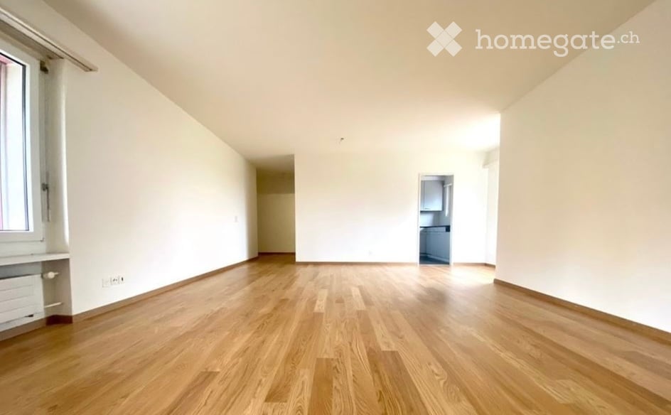 Empty room with wooden flooring, white walls, and large windows. No furniture or equipment present.
