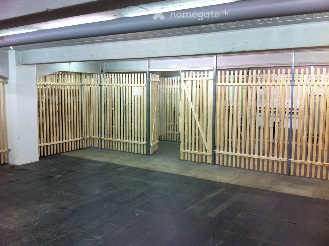 Empty underground parking area with wooden barriers and a concrete floor.