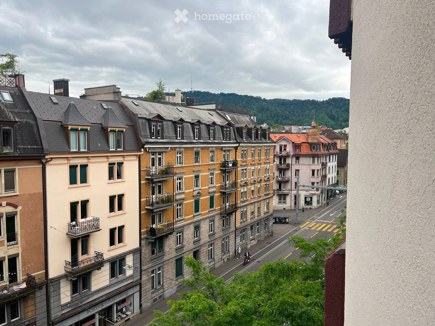 View of a multi-story urban building complex with balconies, windows, and a street below.