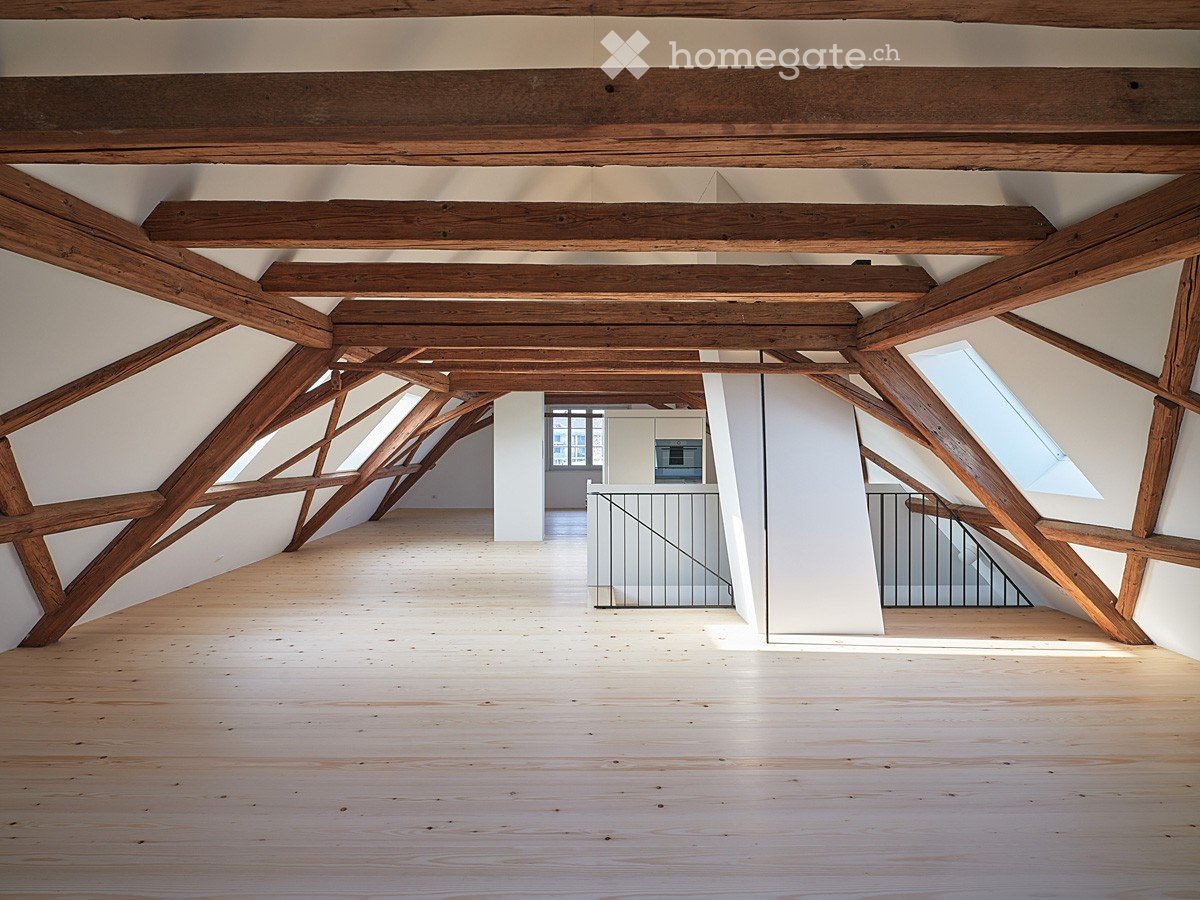 Open, high-ceilinged attic space with exposed wooden beams, wooden flooring, and large skylights. No furniture or equipment visible.