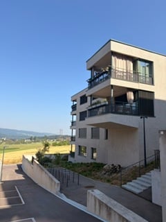 Modern multi-story residential building with balconies, large windows, and a clean, contemporary design.