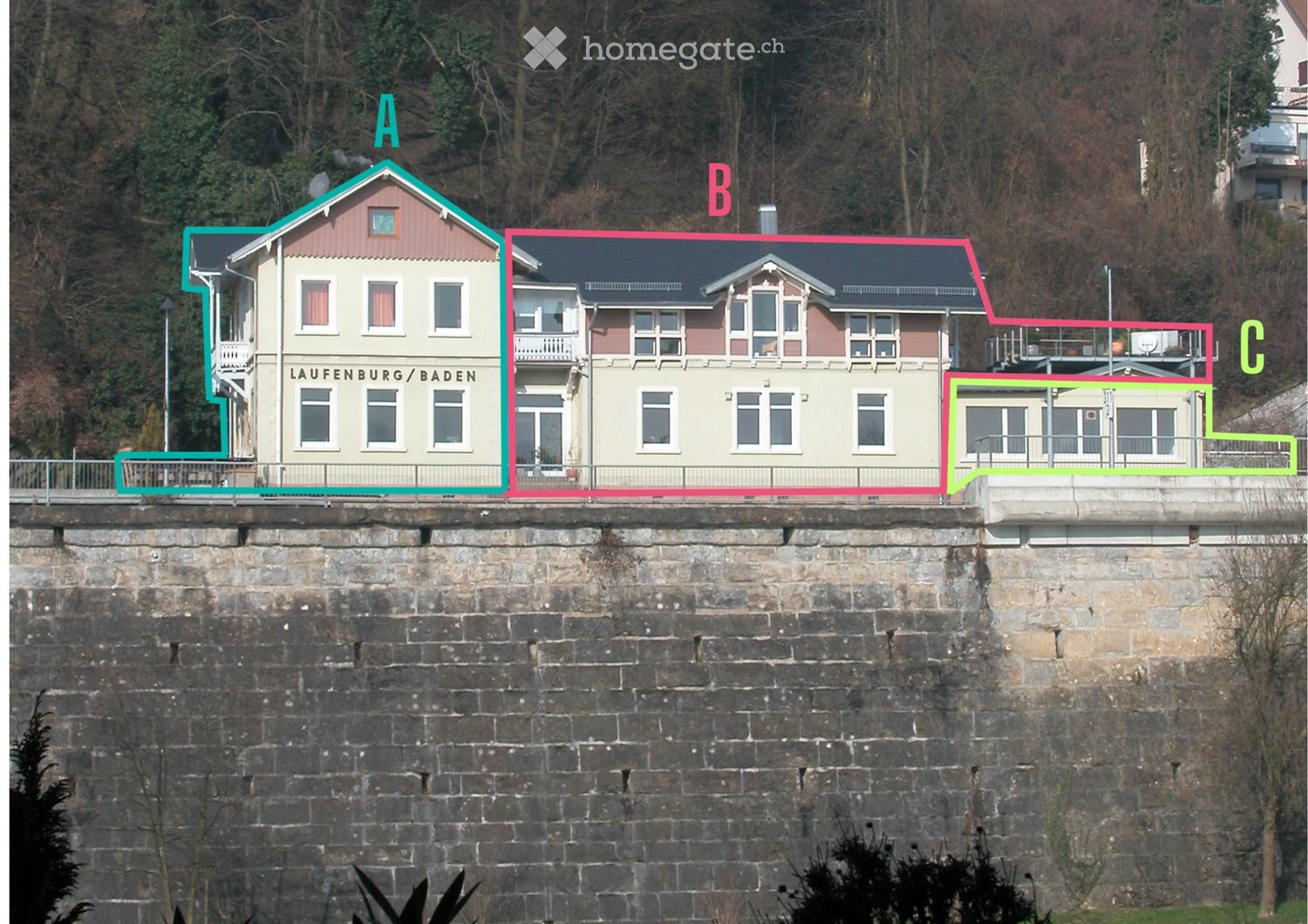 Three multi-story buildings on a raised ground floor above a stone wall, with varied architectural styles and signage.