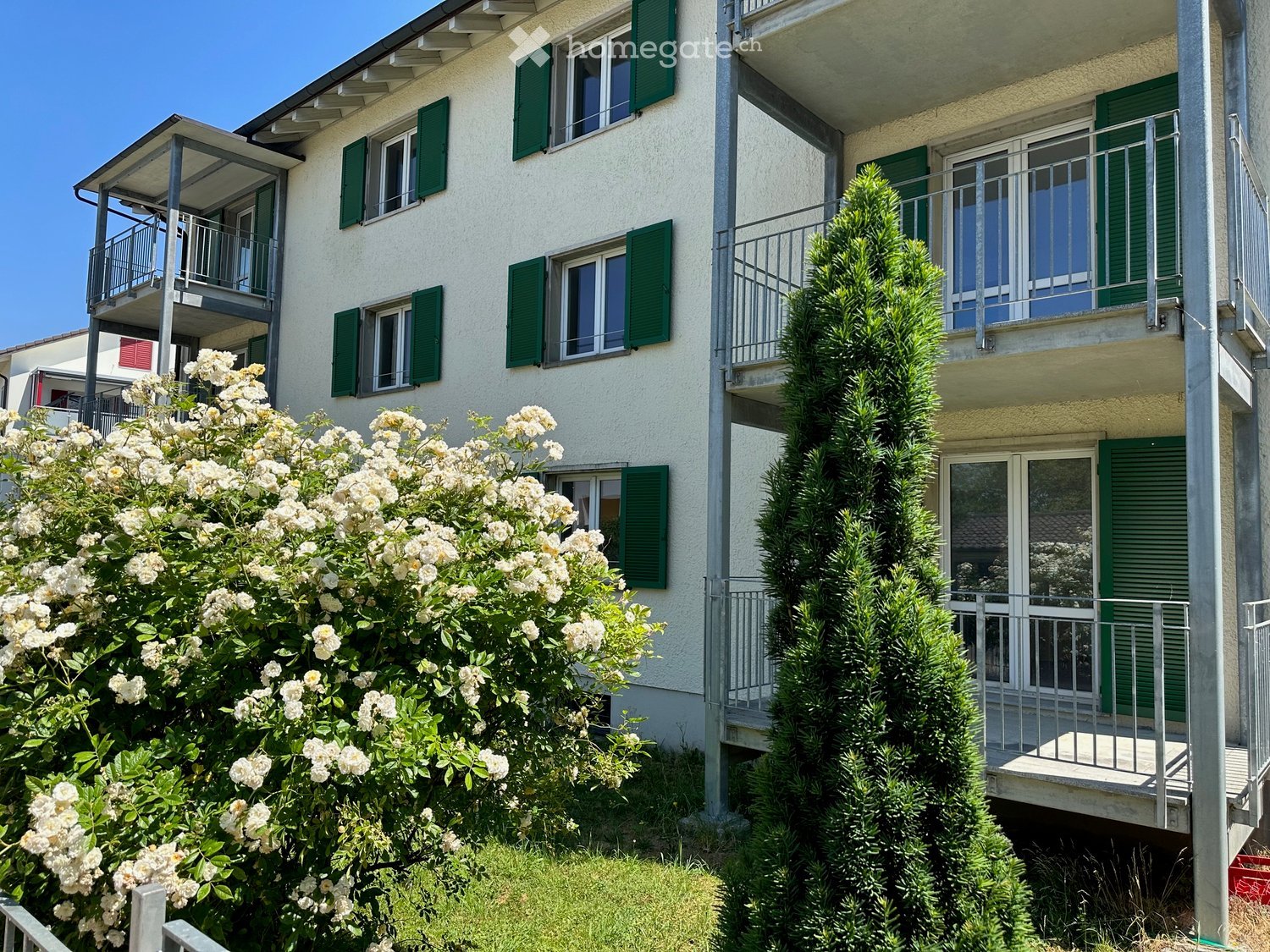 White building, 3 stories, green shutters, 2 balconies