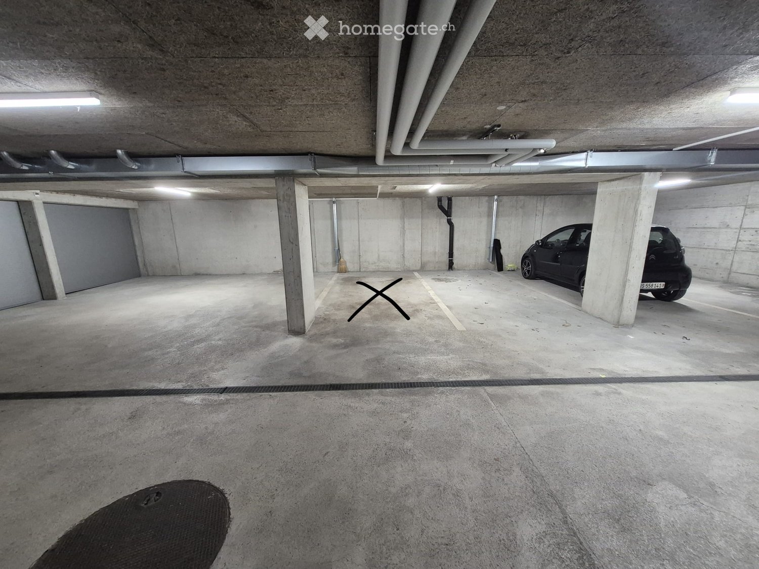 Underground parking garage with concrete pillars, a parked car, and marked parking spaces.
