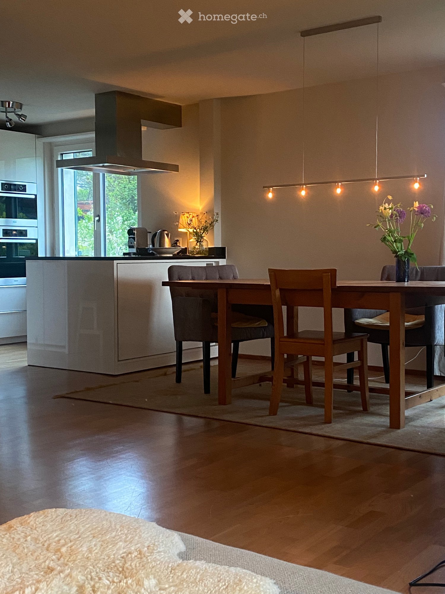 Dining room with wooden table, chairs, kitchen island, and modern appliances