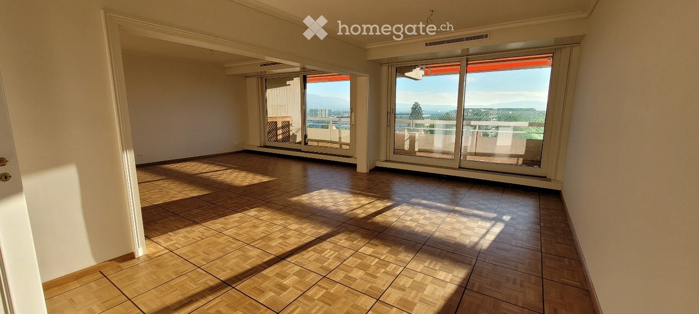 Empty room with wooden flooring, large sliding glass doors leading to a balcony with scenic views.