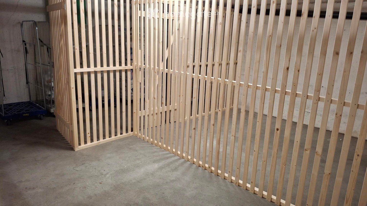 Empty room with unfinished wooden partitions and a concrete floor. No furniture or equipment visible.