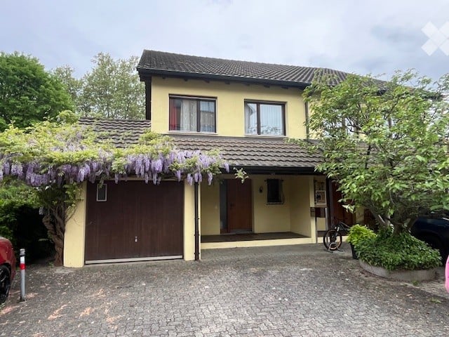 Two-story house with a garage, covered entrance, and climbing plants on the facade.