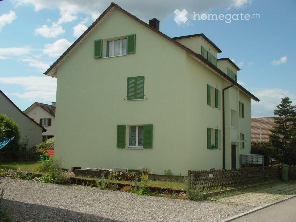 2 story house, green shutters, white walls, brown roof, driveway, fence, green trash bin