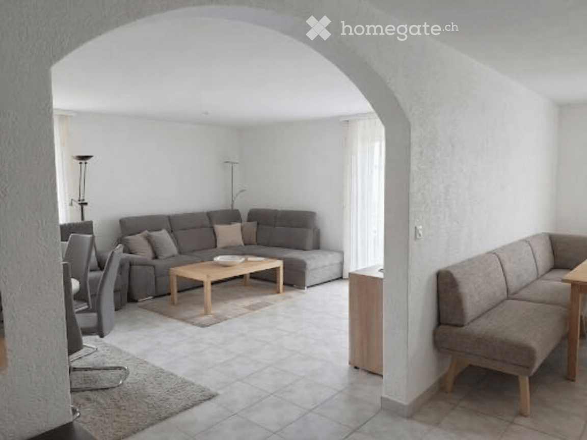 Modern living room with grey sectional sofa, wooden coffee table, dining area with chairs and table, and floor lamps.