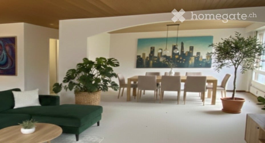 Open-concept living and dining area with a green sectional sofa, wooden coffee table, dining table with chairs, and large potted plants. The space features modern artwork and ample natural light from large windows.