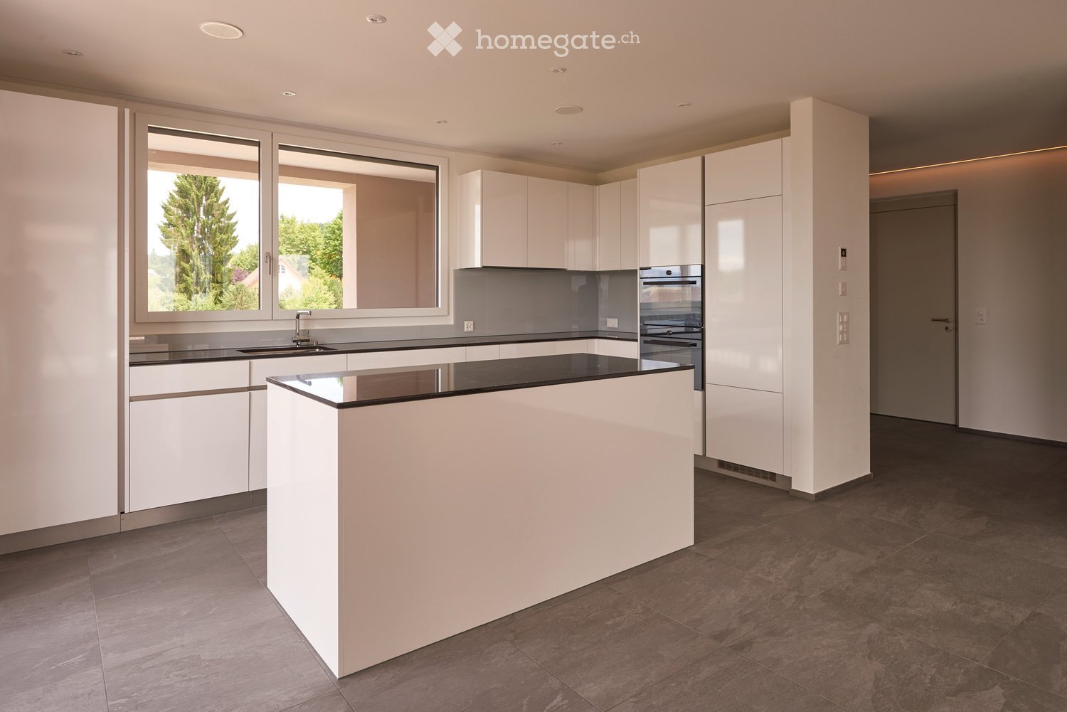 Modern kitchen with white cabinets, black countertop, central island, and stainless steel appliances.