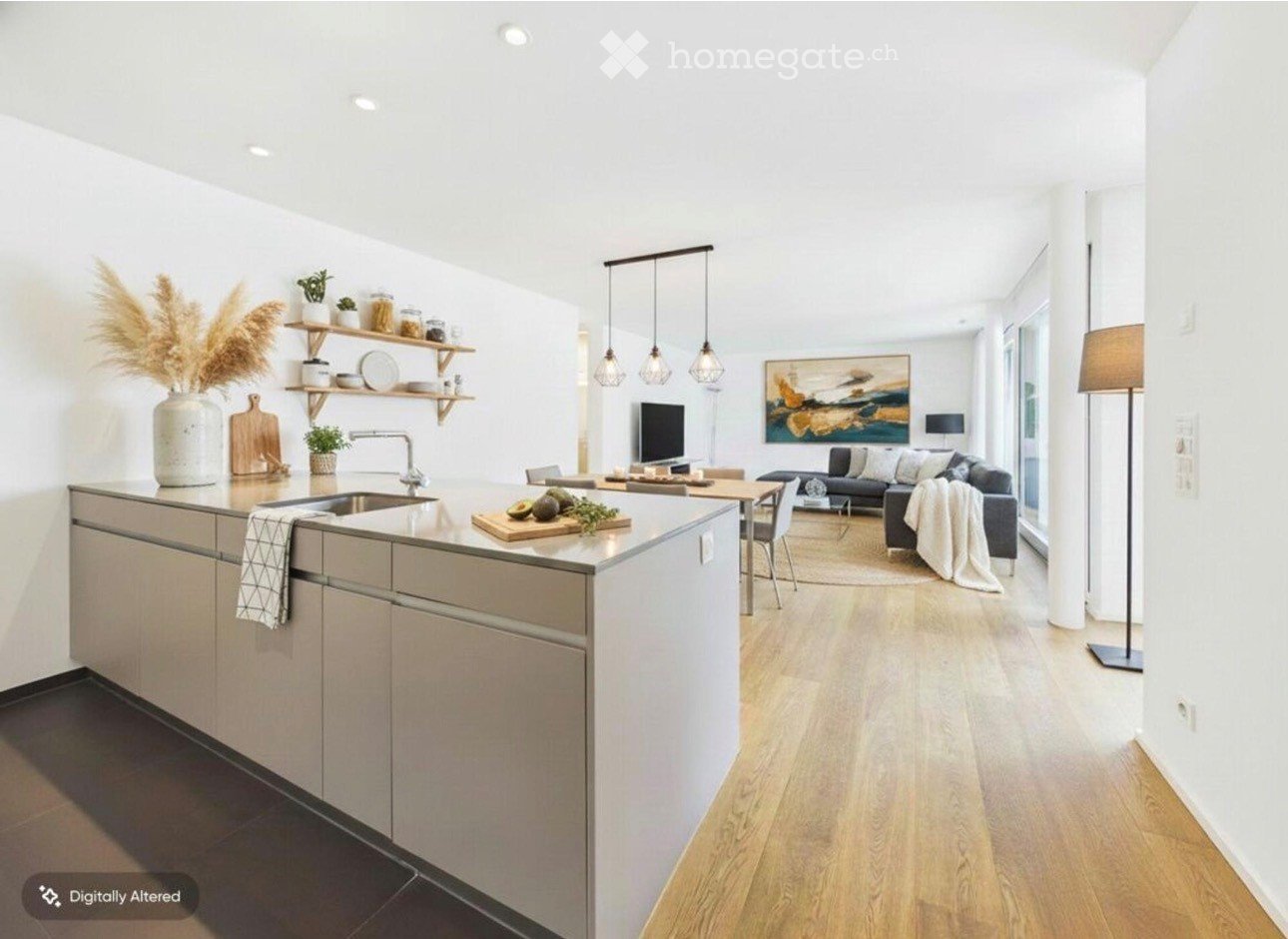 Open-plan living and kitchen area with modern furniture, pendant lights, and a large window. The kitchen features a central island with a sink and shelves, while the living area includes a sofa, coffee table, and a futon.