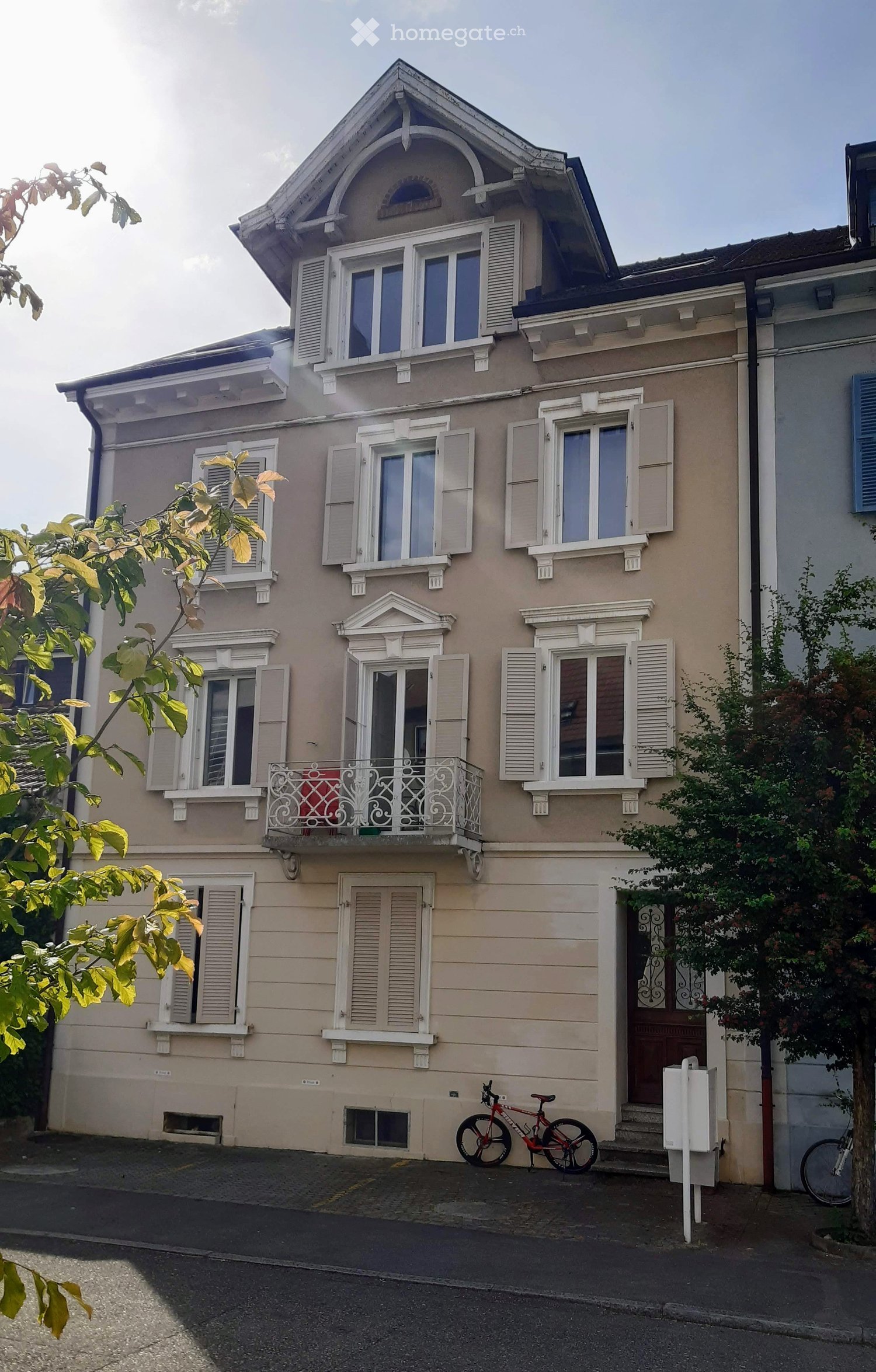 3 story house, beige, white shutters, brown door, balcony, bicycles