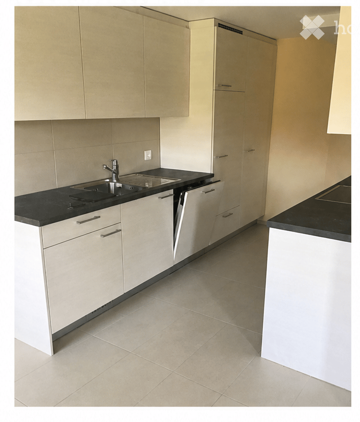 Modern kitchen with light-colored cabinets, black countertop, and stainless steel sink and faucet.