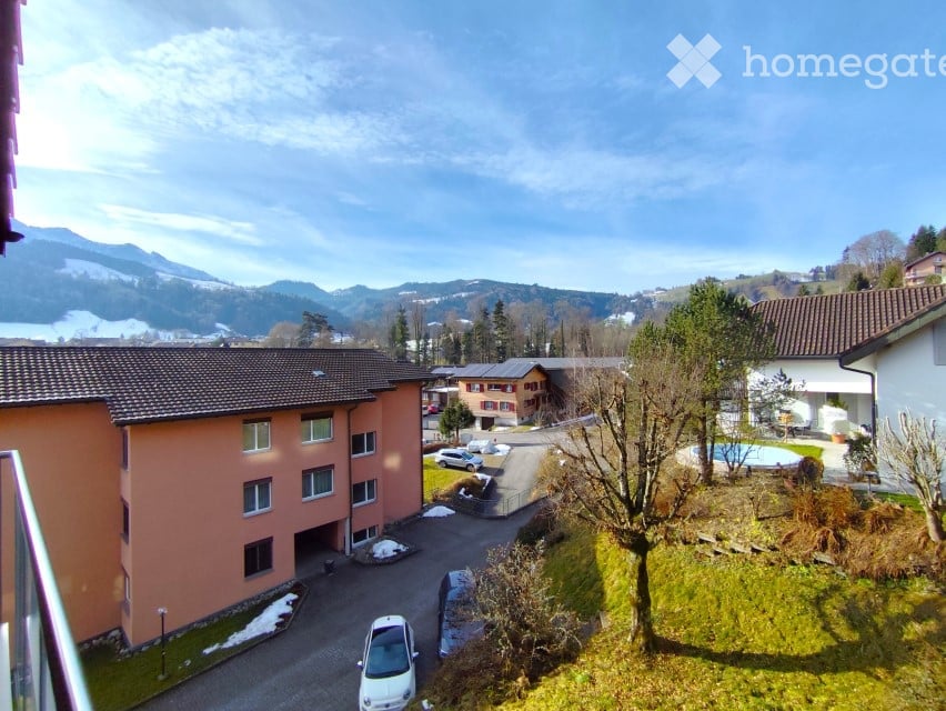 A building with a car parked in front, a swimming pool, and a mountain in the background.