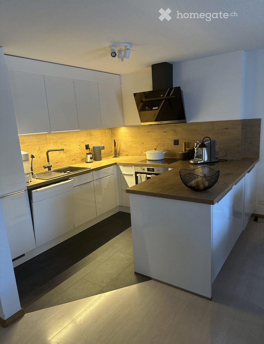 Modern kitchen with white cabinets, wooden countertops, stainless steel appliances, and a central island.