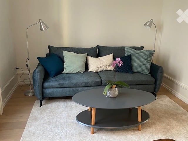 Modern living room with grey sofa, multiple throw pillows, a round coffee table, and a floor lamp on either side.