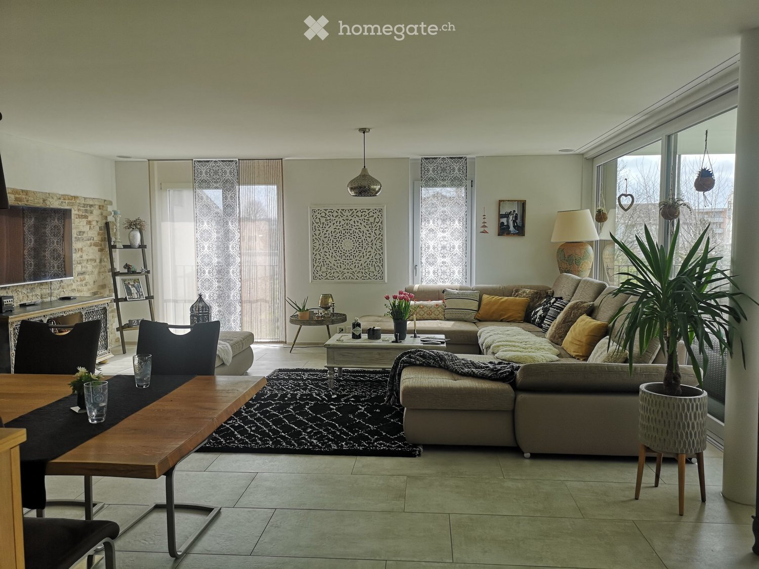 Modern living room with a large sectional sofa, coffee table, dining table, chairs, lamps, and decorative items.