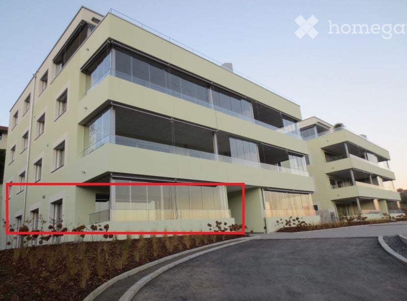 Modern multi-story residential building with light green facade, large windows, and balconies.