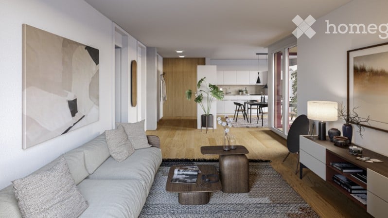 Modern living room with a grey sofa, coffee table, side table, and a potted plant. The room features a sleek design with a large abstract painting on the wall and a view into a contemporary kitchen area with white cabinets and a dining table.