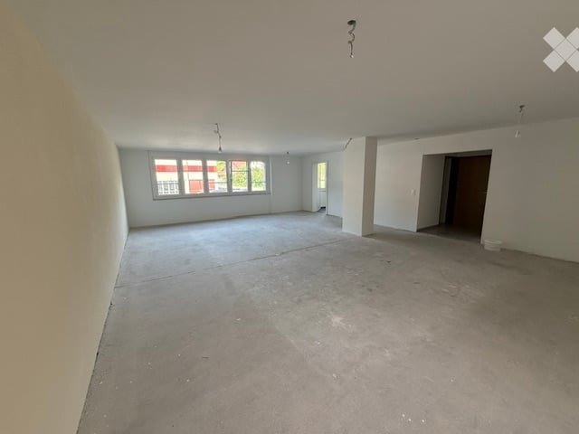 Empty room with bare walls and concrete floor, large windows, no furniture or equipment.