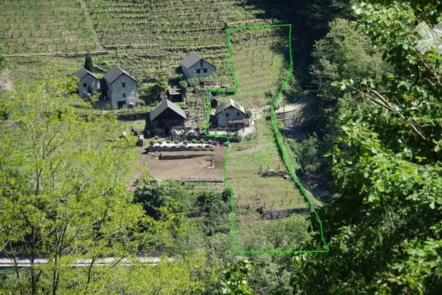 Aerial view of a rural property with multiple houses, surrounded by lush greenery and terraced fields.