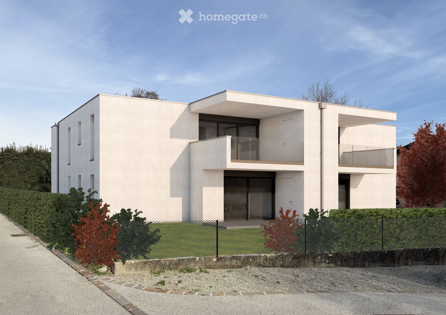Modern two-story house with white facade, large windows, and balconies. The house features a raised ground floor and is surrounded by a low hedge and small garden area.