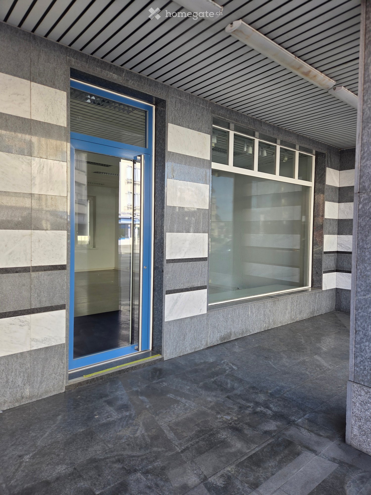 Commercial building with glass door and windows, marble and gray wall, tiled floor