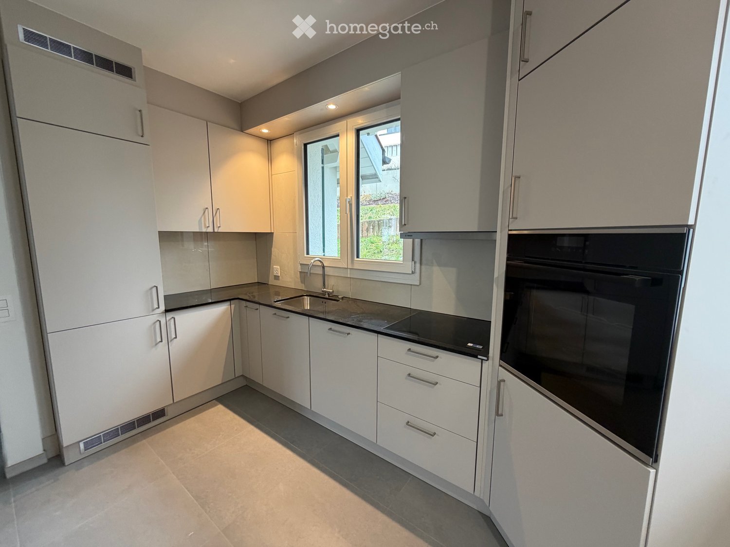 modern kitchen, white cabinets, black countertops, integrated sink, built-in oven and dishwasher