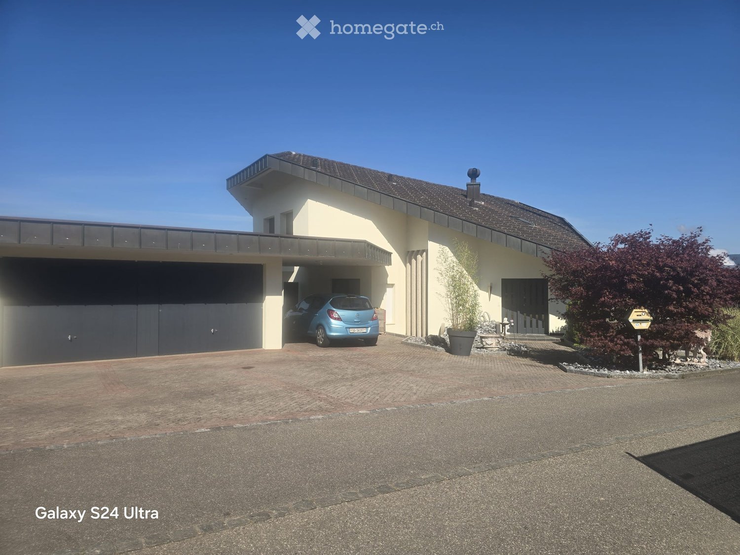 Modern two-story house with a garage, a balcony, and a well-maintained garden area.