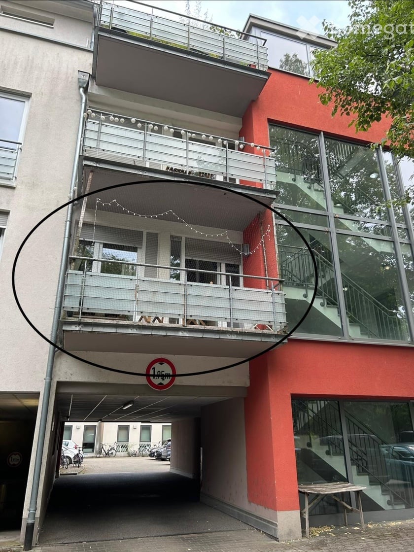 Multi-story building with balconies, garage entrance, and modern glass facade.