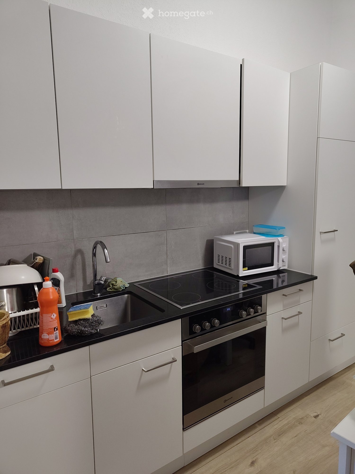 Modern kitchen with white cabinets, stainless steel appliances, and a black countertop.