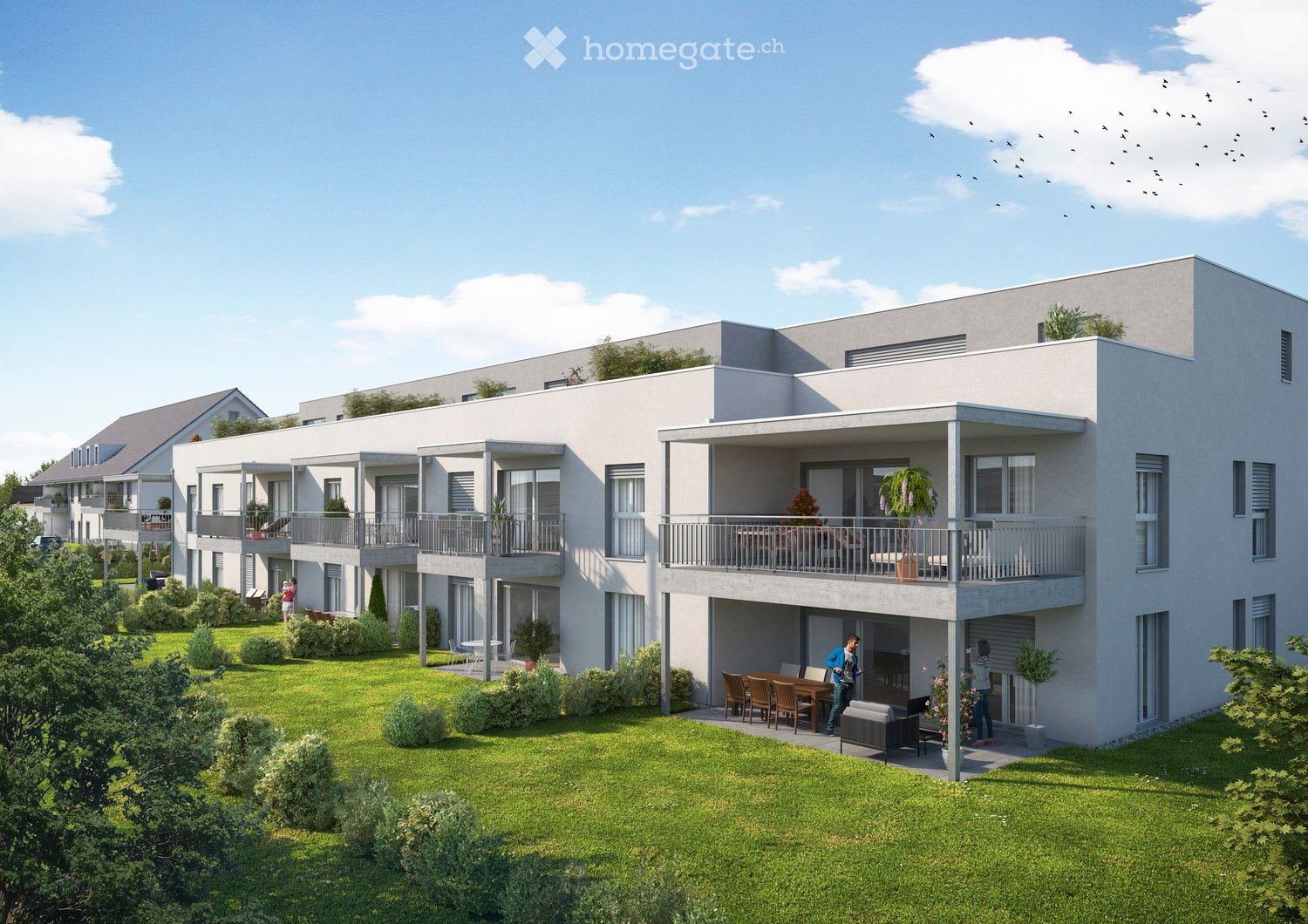 Modern multi-story residential building with balconies, surrounded by green lawn and small trees. Residents are seen enjoying the outdoor area with tables and chairs.