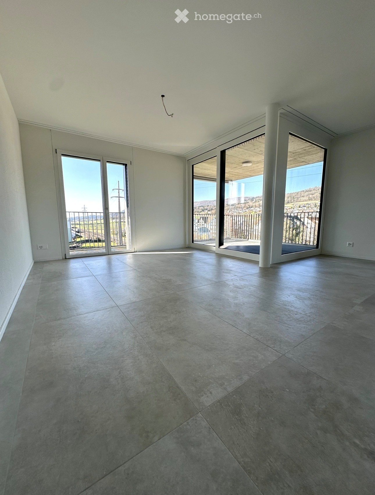 Empty room with large sliding glass doors leading to a balcony, tiled floor, and white walls.